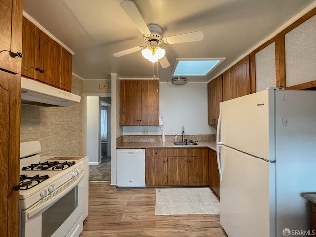 kitchen with a skylight, sink, ornamental molding, white appliances, and light hardwood / wood-style flooring