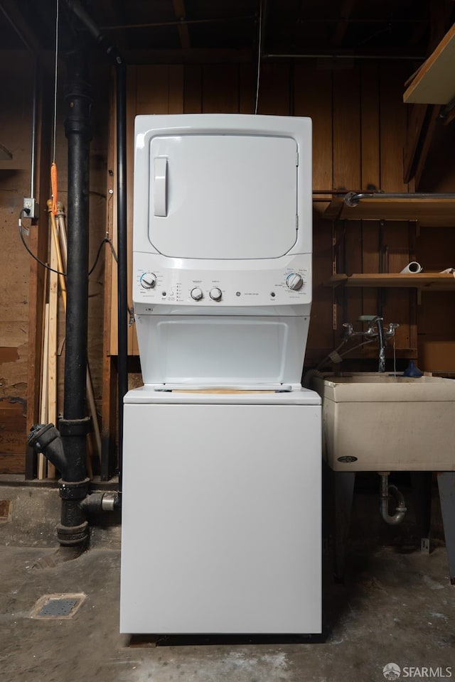 washroom with stacked washing maching and dryer and sink