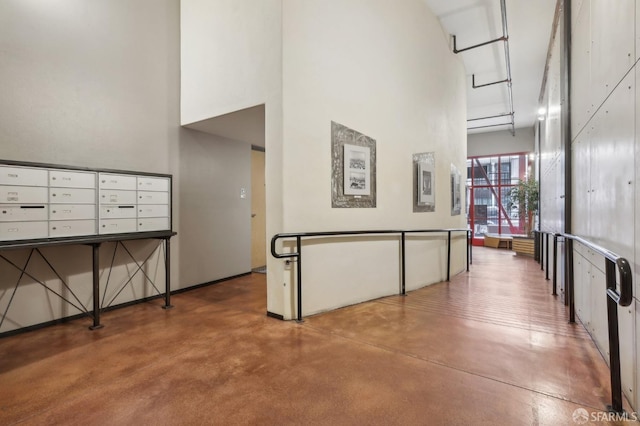 interior space featuring concrete flooring, a towering ceiling, and a mail area