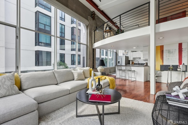 living room with wood-type flooring, sink, and a high ceiling