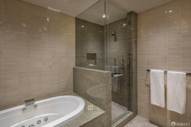 bathroom featuring shower with separate bathtub and tile walls