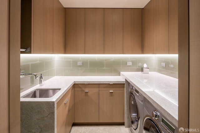 clothes washing area with washing machine and clothes dryer and sink