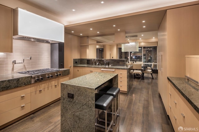 kitchen featuring a center island, a kitchen breakfast bar, decorative light fixtures, dark hardwood / wood-style flooring, and stainless steel gas cooktop