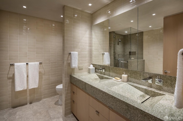 bathroom with vanity, tile patterned flooring, toilet, tile walls, and an enclosed shower