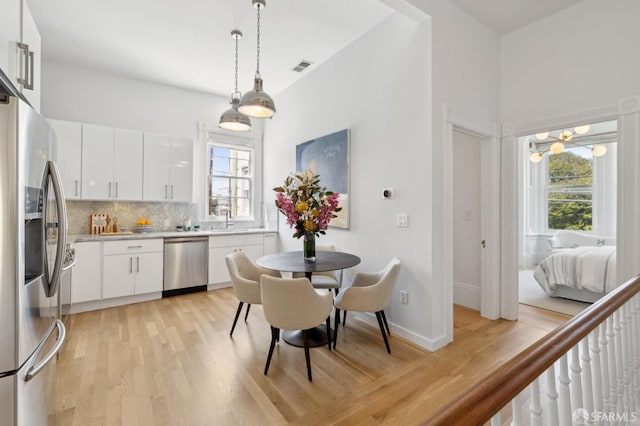 3031 20th St, San Francisco, CA 94110 - kitchen featuring appliances with stainless steel finishes, light wood-style floors, light countertops, tasteful backsplash, and pendant lighting