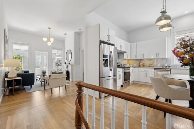 3031 20th St, San Francisco, CA 94110 - kitchen with stainless steel appliances, backsplash, pendant lighting, white cabinetry, and light countertops