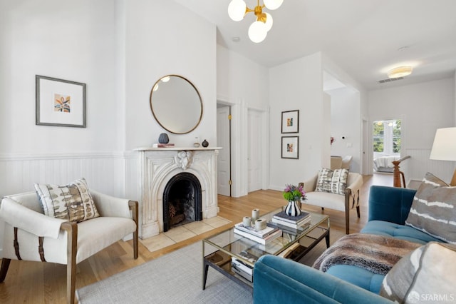 3031 20th St, San Francisco, CA 94110 - living area featuring a chandelier, light wood finished floors, a fireplace with flush hearth, and wainscoting