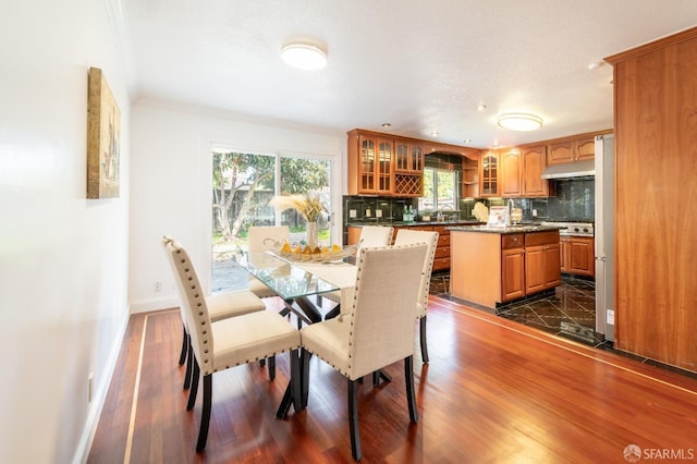 dining space featuring crown molding, dark wood finished floors, and baseboards