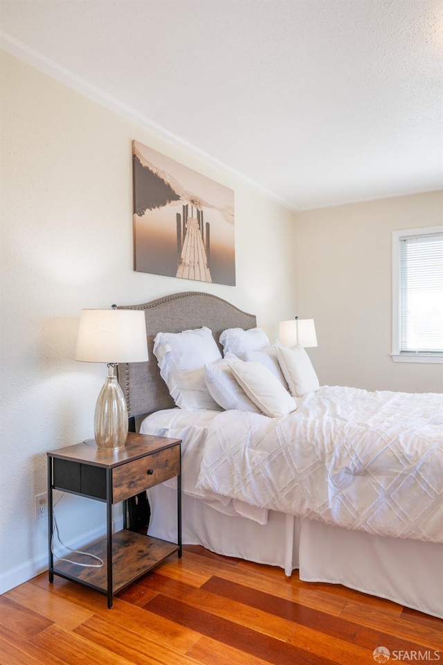 bedroom with baseboards and wood finished floors