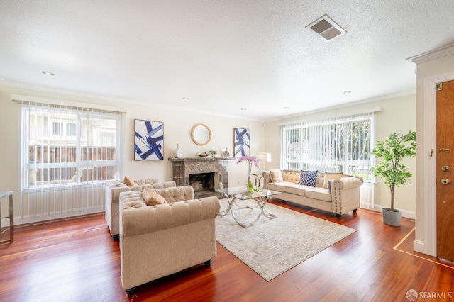 living area featuring a textured ceiling, ornamental molding, dark wood finished floors, and visible vents