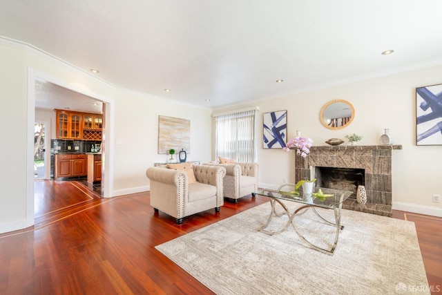 living area featuring ornamental molding, dark wood-type flooring, and a tile fireplace