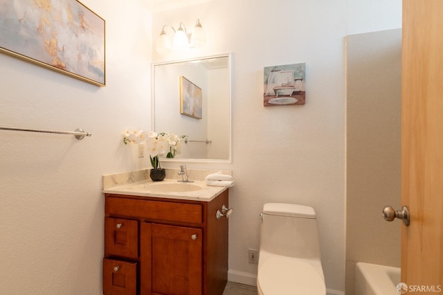 bathroom featuring toilet, a tub to relax in, and vanity