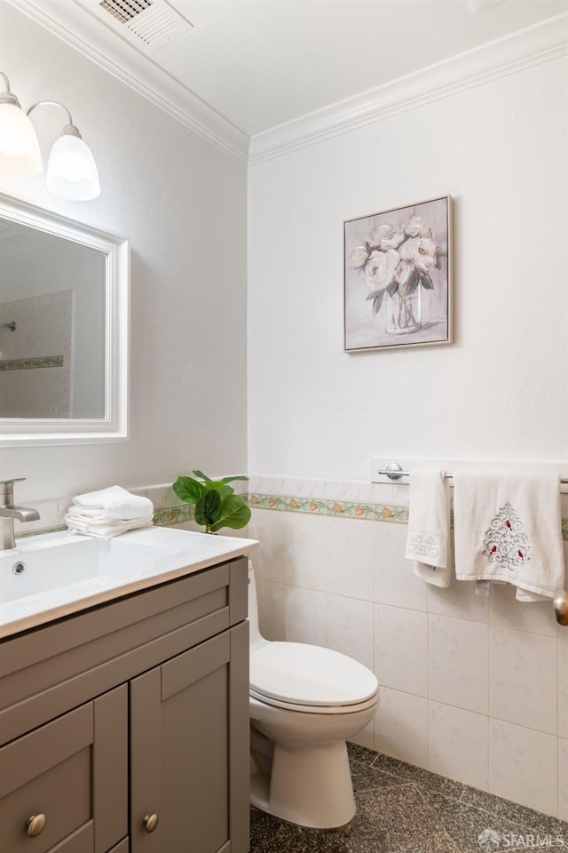 half bathroom with tile walls, visible vents, toilet, ornamental molding, and vanity