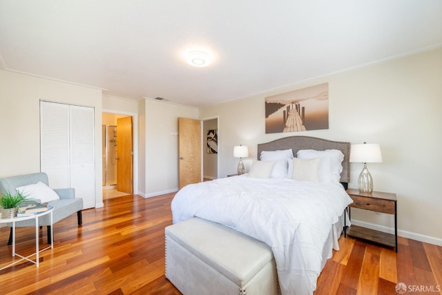 bedroom with wood finished floors, visible vents, and baseboards