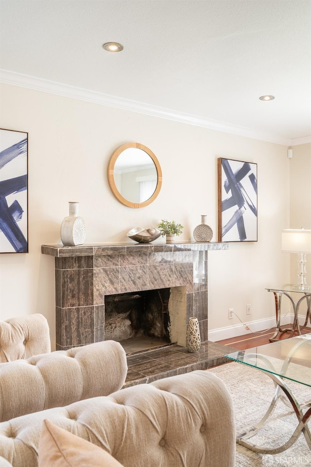 living area with a tile fireplace, recessed lighting, wood finished floors, baseboards, and crown molding