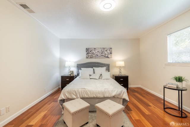 bedroom featuring wood finished floors, visible vents, and baseboards