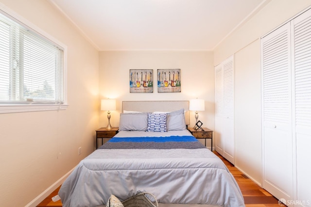 bedroom featuring light wood-type flooring, baseboards, and multiple closets