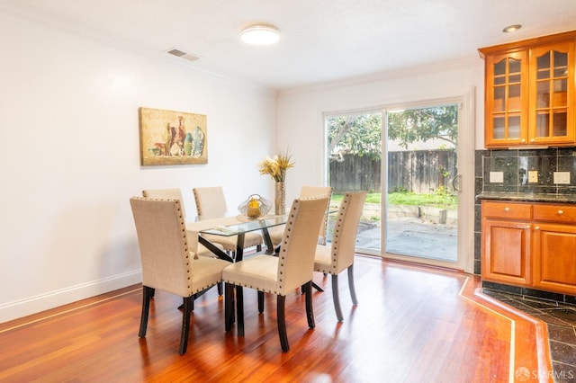 dining area with visible vents, crown molding, baseboards, and wood finished floors