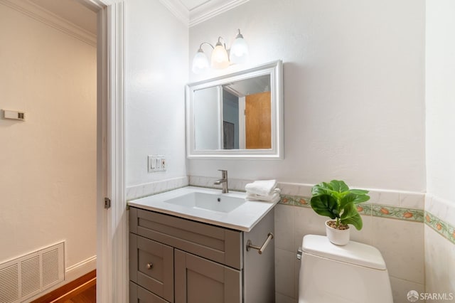 bathroom featuring toilet, a wainscoted wall, visible vents, and crown molding