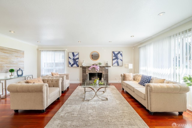 living area featuring ornamental molding, a tile fireplace, dark wood finished floors, and baseboards