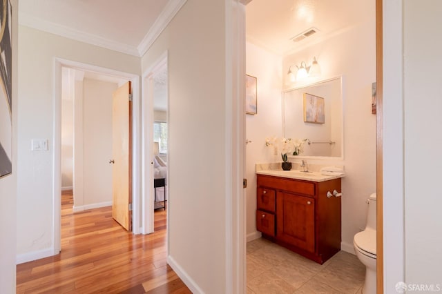 bathroom featuring visible vents, toilet, wood finished floors, crown molding, and vanity