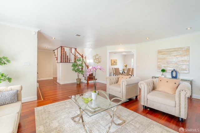 living area featuring baseboards, visible vents, stairway, wood finished floors, and crown molding