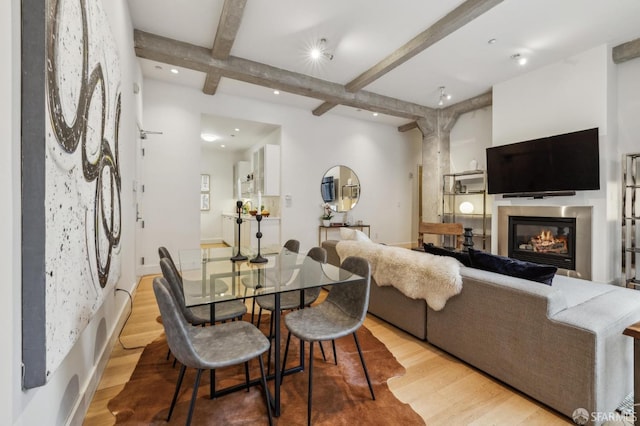 dining space featuring light hardwood / wood-style floors and beamed ceiling