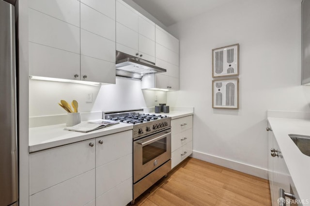 kitchen with stainless steel range, light hardwood / wood-style flooring, and white cabinets