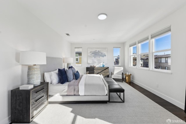 bedroom with dark hardwood / wood-style flooring and multiple windows