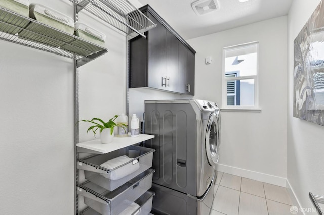 washroom featuring cabinets, light tile patterned floors, and washing machine and clothes dryer