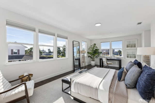 bedroom with dark hardwood / wood-style floors and multiple windows