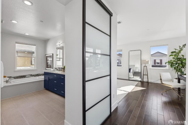 bathroom with hardwood / wood-style flooring, a washtub, and vanity