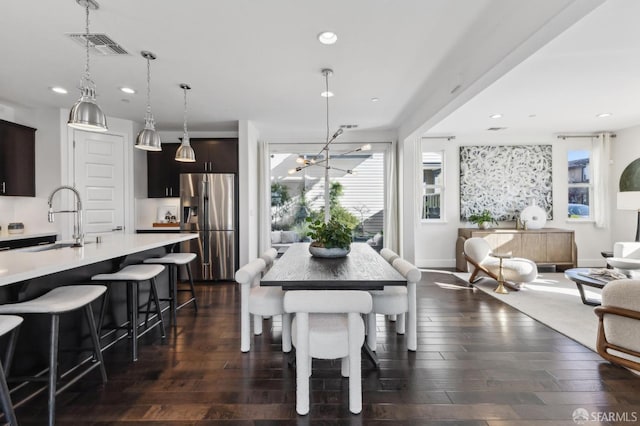 dining area with dark wood-type flooring, sink, and an inviting chandelier