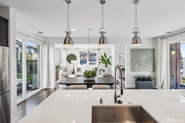 kitchen featuring sink, stainless steel refrigerator, pendant lighting, and dark wood-type flooring