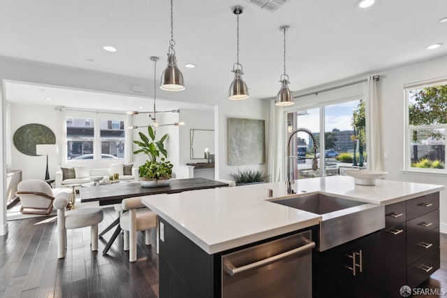 kitchen featuring dishwasher, dark hardwood / wood-style flooring, sink, decorative light fixtures, and an island with sink