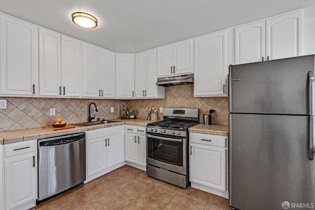 1187 Hollister St, San Francisco, CA 94124 - kitchen featuring stainless steel appliances, a sink, under cabinet range hood, light tile patterned floors, and backsplash