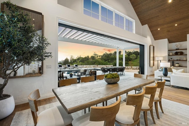 dining area with a high ceiling, wood ceiling, and light wood-type flooring