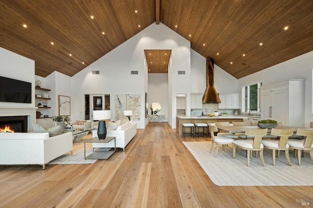 living room with high vaulted ceiling, light wood-type flooring, and sink