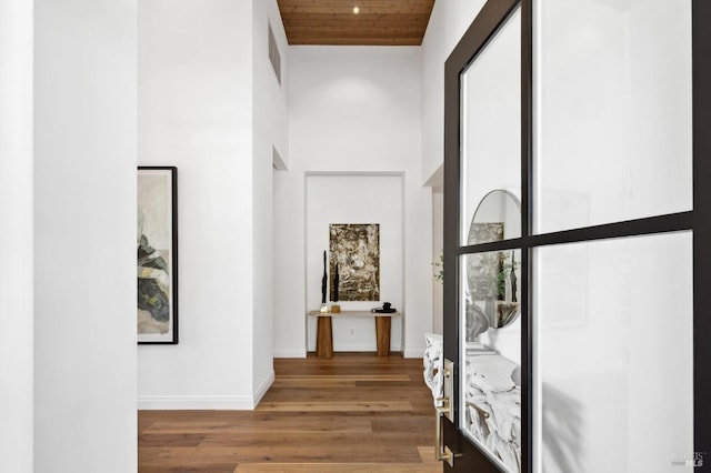 hall with a towering ceiling, hardwood / wood-style floors, and wood ceiling