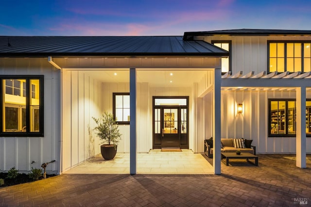 back house at dusk with outdoor lounge area and a patio