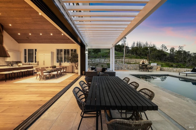 patio terrace at dusk featuring sink and a pergola