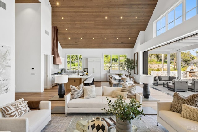 living room featuring light wood-type flooring, sink, a high ceiling, and wooden ceiling