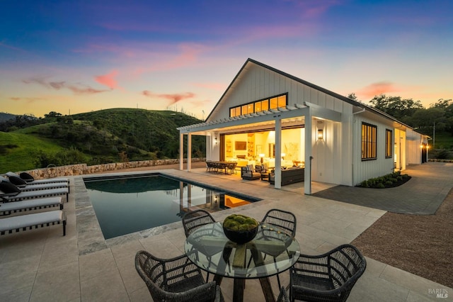 back house at dusk featuring an outdoor living space, a patio area, and a mountain view