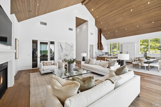 living room featuring wooden ceiling, beam ceiling, light hardwood / wood-style floors, and high vaulted ceiling