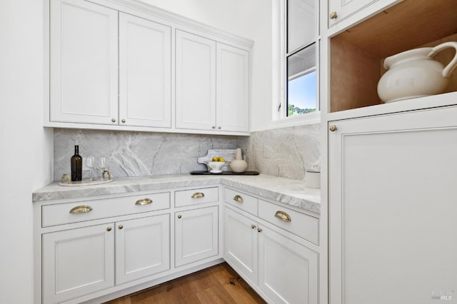 kitchen with white cabinets, decorative backsplash, dark wood-type flooring, and light stone counters