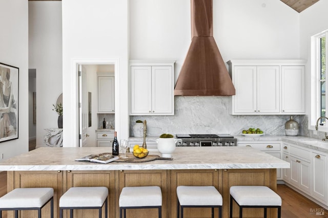 kitchen featuring tasteful backsplash, range, white cabinetry, and a center island