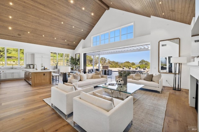 living room with light wood-type flooring, sink, beam ceiling, and high vaulted ceiling