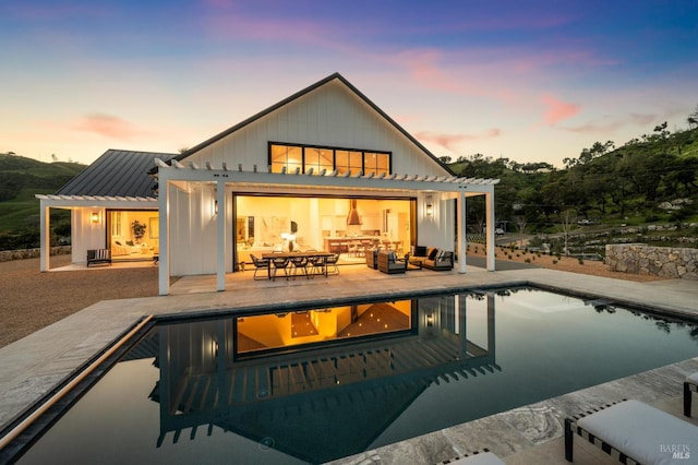 back house at dusk featuring a pergola and a patio