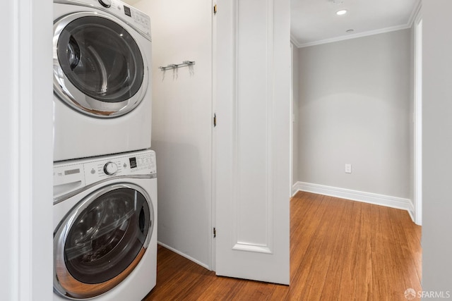 washroom featuring wood-type flooring, crown molding, and stacked washer / drying machine