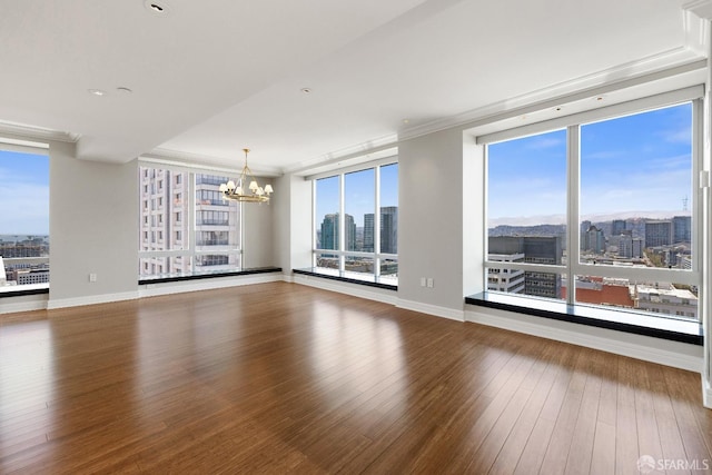 empty room with hardwood / wood-style flooring, a healthy amount of sunlight, and a notable chandelier